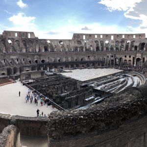 Inside of the Colosseum in Rome. There are tourists walking around the ancient site.