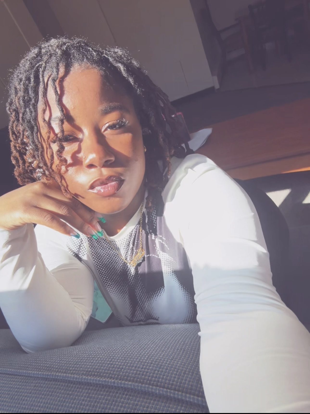 UConn student with short black locs poses for selfie wearing a white long sleeve shirt.