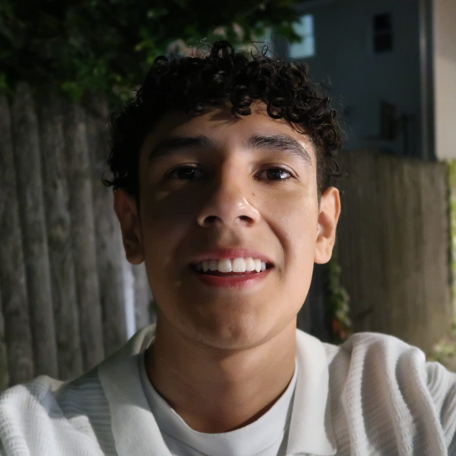 Male student smiling at camera on a dark street.